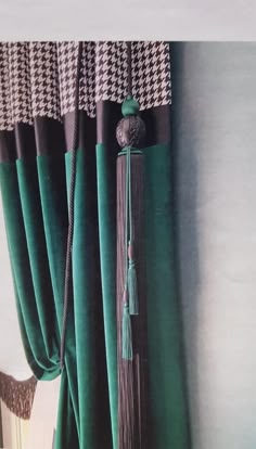 a green curtain with tassels hanging from it's side in front of a window