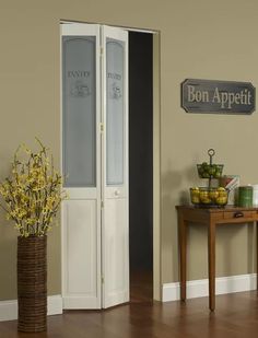 a room with a table, vase and door on the wall that says bon appetit