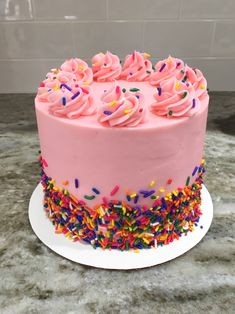 a pink frosted cake with sprinkles on top