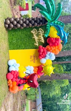 balloons and streamers are arranged on the grass for an outdoor birthday party with palm trees in the background