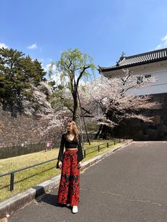 a woman is standing in front of some trees