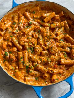 a blue skillet filled with pasta and sauce