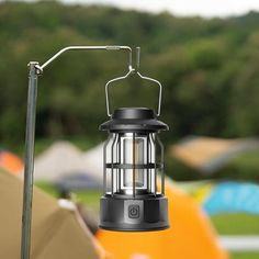 a black lantern hanging from a metal pole next to an orange tent in the background