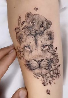 a woman's arm with a lion tattoo on it and flowers around the wrist