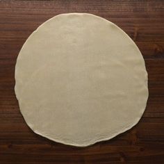 an uncooked pizza dough sitting on top of a wooden table