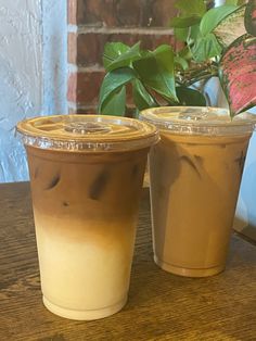 two iced coffees sitting on top of a wooden table