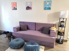 a living room with a purple couch and ottoman