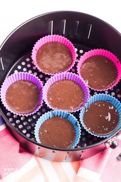 chocolate cupcakes in pink and blue paper liners on a black pan with polka dots