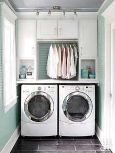 a washer and dryer in a laundry room with blue walls, black tile flooring and white cabinets