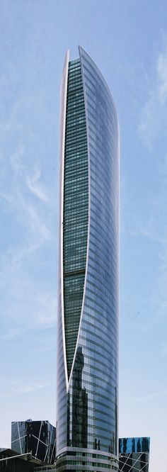 a very tall building sitting on top of a lush green field in front of a blue sky