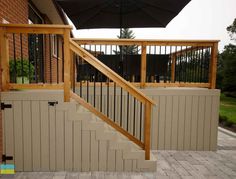 an umbrella is on top of a wooden railing next to a brick wall and stairs