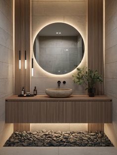 a bathroom with a round mirror above the sink and rocks on the ground below it