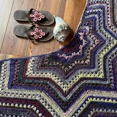 a crocheted blanket and pair of flip flops on the floor