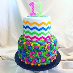 a multicolored birthday cake with the number one on it's top tier