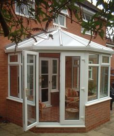 an orange brick house with a white roof and glass doors on the side of it