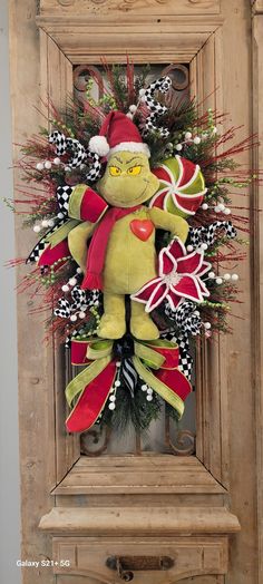 a christmas wreath with a stuffed animal in it and decorations on the front door frame