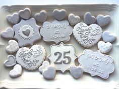 decorated cookies in the shape of hearts on a white platter with 25th anniversary date