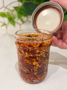 a jar filled with food sitting on top of a white counter next to a plant