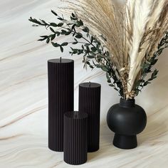 three tall black vases sitting next to each other