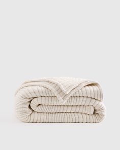 three folded blankets stacked on top of each other in white linen, with one folded over the