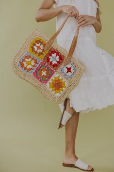 a woman carrying a crocheted bag with flowers on it