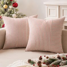 two red and white striped pillows sitting on top of a couch next to a christmas tree