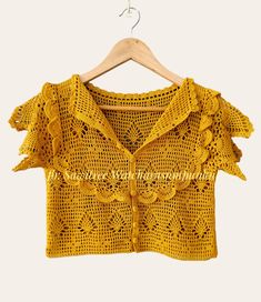 a yellow crocheted top hanging on a wooden hanger