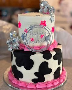 a birthday cake decorated with black and white polka dots, pink ruffles and silver decorations