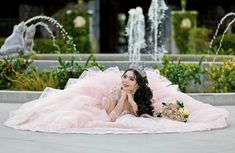 a woman laying on the ground wearing a pink dress and holding a bouquet in her hand