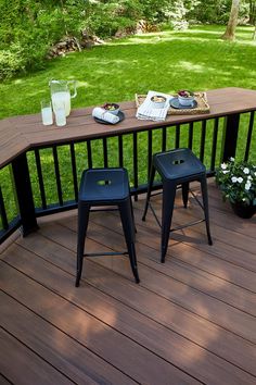 two stools sitting on top of a wooden deck next to a table with drinks