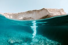 an iceberg in the middle of the ocean with blue water and rocks below it