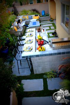 an outdoor dining area with table, chairs and food on it in the middle of a yard