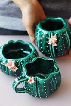 two green vases sitting on top of a table next to each other with flowers in them