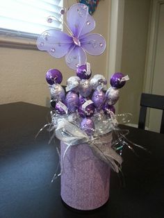 a purple vase filled with chocolates and a butterfly decoration on top of a table