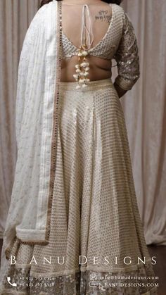 Single dori V neckline back design accented with stunning white & gold tassels. Flared georgette double border sequin accented lengha skirt adorned with huge stunning gold tassels. Embroidered Georgette Dupatta. Included in purchase: lehenga, blouse and dupatta. #Lehenga #indianfashion #galanight Lehenga For Diwali, Monochrome Lehenga, Georgette Lengha, Lengha Skirt, Gala Outfit, Georgette Dupatta, Sequin Blouse, Lehenga Blouse, Indian Blouse