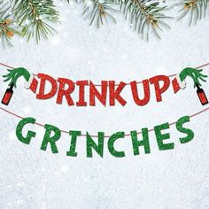 the words drink up grinies are hanging from a christmas tree branch in the snow