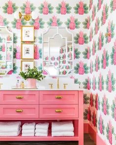 a bathroom with pink drawers and wallpaper