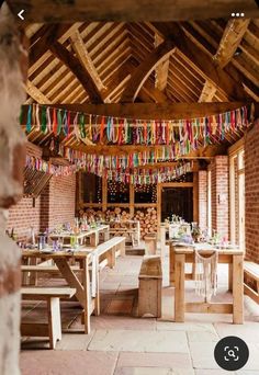 the inside of a building with tables and benches covered in colorful streamers hanging from the ceiling