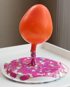 an orange lollipop sticking out of a paper plate