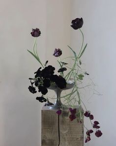 a vase filled with flowers sitting on top of a wooden block