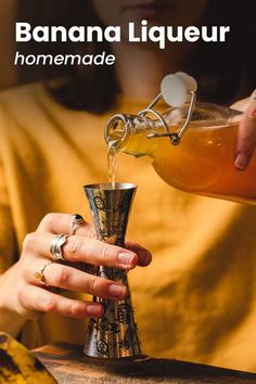 a woman pours liquid into a cup from a metal funneler, with the words banana liqueur on it