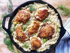 chicken and pasta in a cast iron skillet on a wooden table with fresh herbs