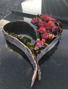 flowers are placed in the shape of a boat on top of a black stone table