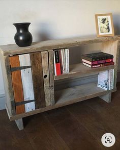 a book shelf made out of wood with books on top and a vase next to it