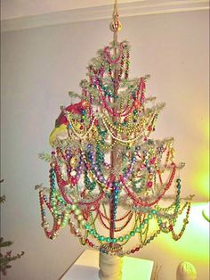 a christmas tree made out of beads on a table next to a lamp and other decorations