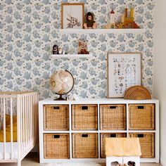 a baby's room with wallpaper and baskets on the floor