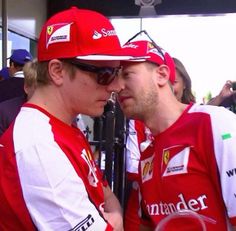 two men in red and white shirts standing next to each other at a race track