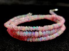 three strands of pink opalite beads with silver clasps on a black surface