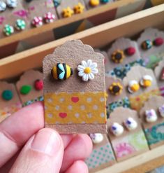 a person holding up a piece of paper with buttons on it and flowers in the background