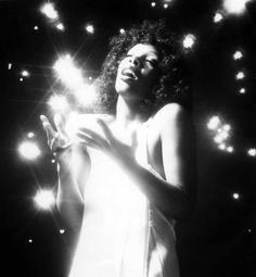 a black and white photo of a woman holding a cell phone in front of some lights